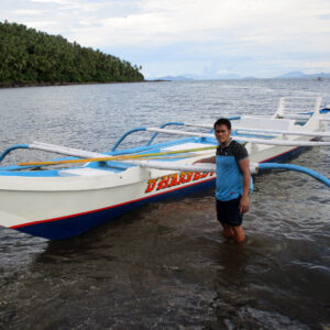 missionary standing in water with new boat