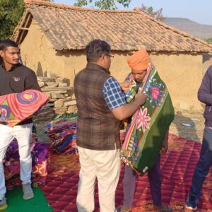 man wrapping a colorful blanket around another man standing outside