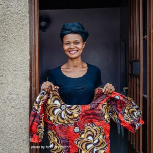 Woman standing in door frame holding brightly patterned dress
