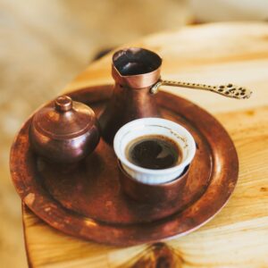 A cup of coffee is served with a pot and sugar bowl.