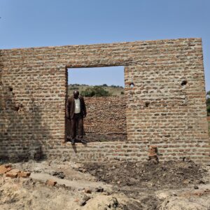 man standing in door frame of brick building construction site